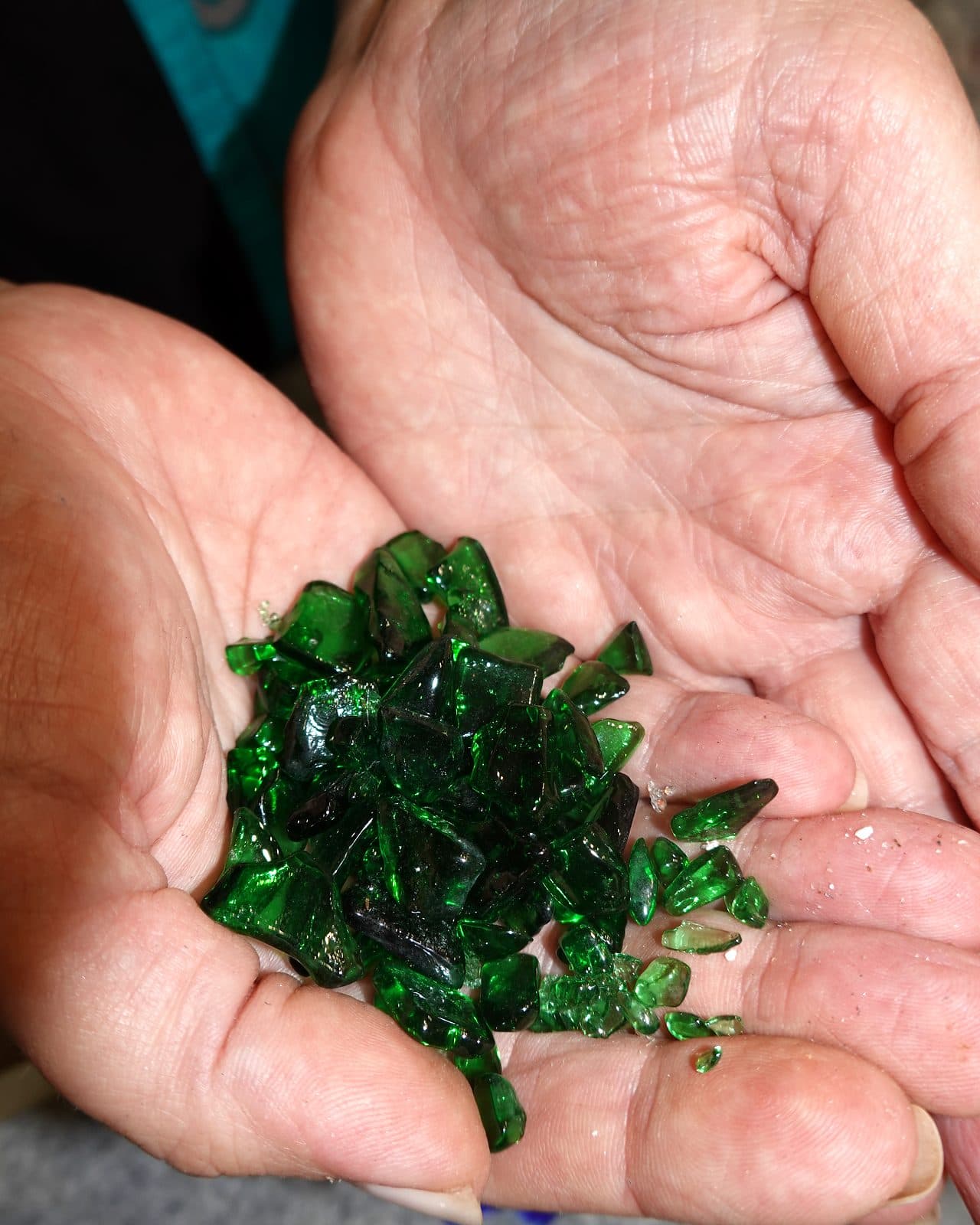 Hands holding a handful of green glass